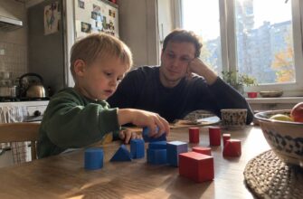A child and dad comparing wooden shapes at a table