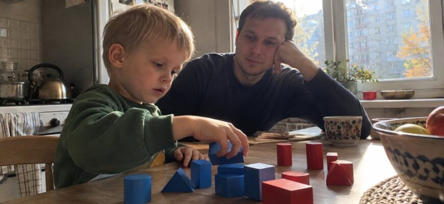 A child and dad comparing wooden shapes at a table