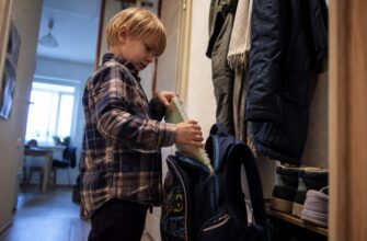 A boy packing his school backpack independently