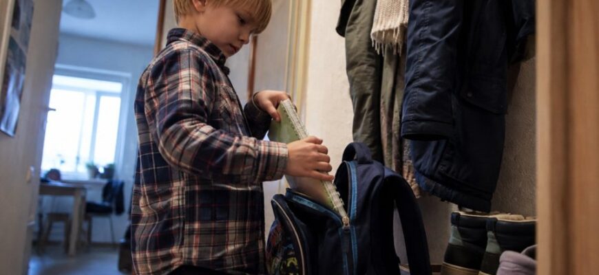 A boy packing his school backpack independently