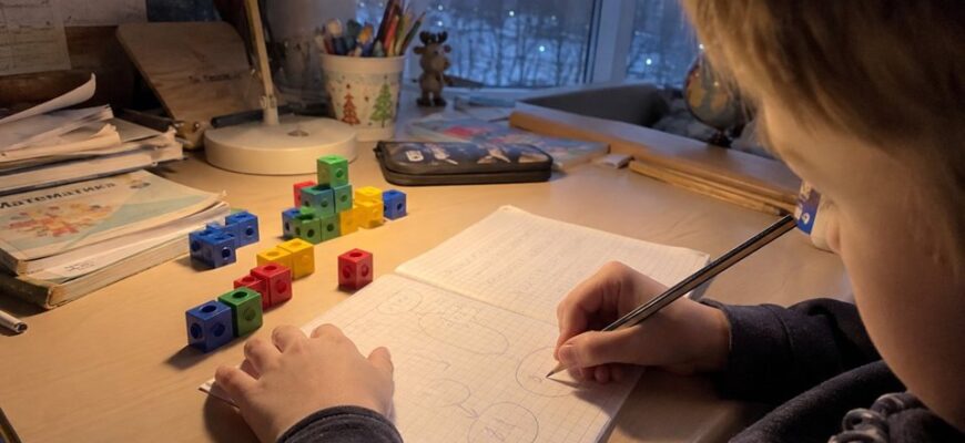 A child drawing a word-problem diagram under a desk lamp