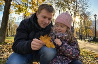 A dad and daughter examining an autumn leaf with a magnifying glass